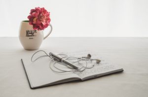 A notebook with headphones and a flower in it.