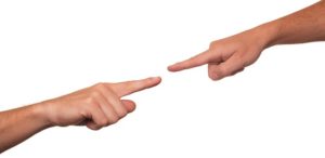 Two hands are pointing to each other with one hand holding a finger.