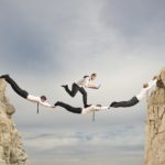 A group of people jumping over rocks in the air.