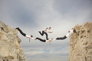 A group of people jumping over rocks in the air.