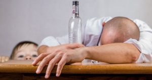 A man is sleeping on the table with his hands on the counter.