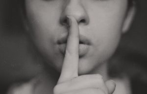 A woman with her finger on the lips.