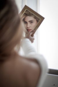 A woman looking at her reflection in the mirror.