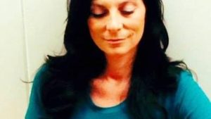 A woman with long black hair wearing a blue shirt.