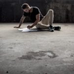 A man sitting on the ground writing with paper