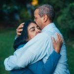 A man and woman hugging in the grass.