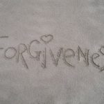 A word written in the sand that says " forgiveness ".