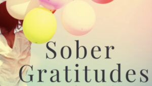 A woman holding balloons with the words sober gratitudes in front of her.