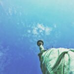 A statue of liberty is seen from below.