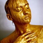 A woman with gold paint on her body.