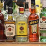 A variety of alcohol bottles lined up on top of each other.